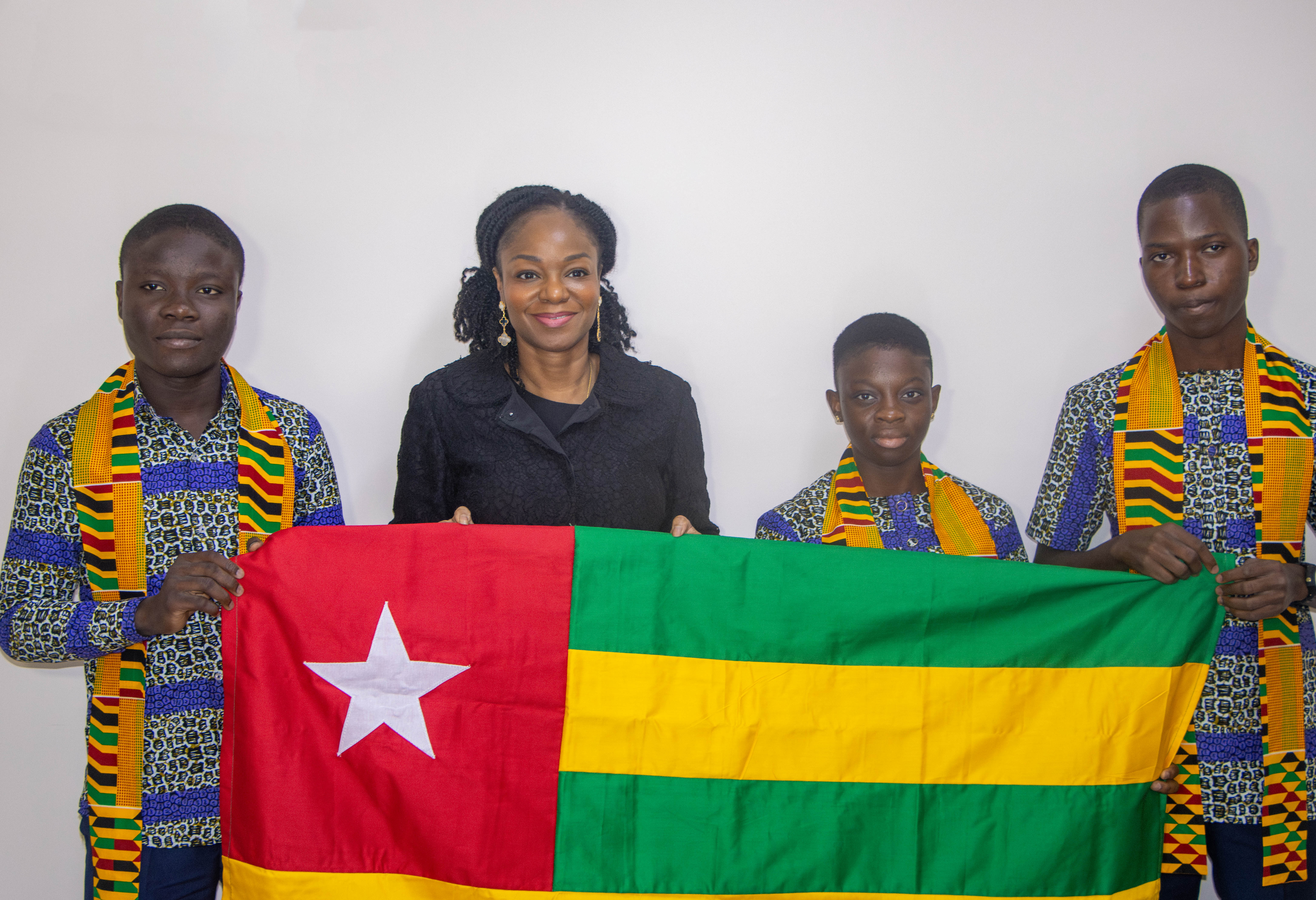 Cina Lawson remettant le drapeau national aux 3 représentants du Togo aux Olympiades Panafricaines de Mathématiques